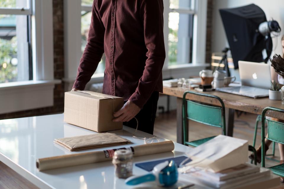 A seller packing orders into cardboard boxes at a desk